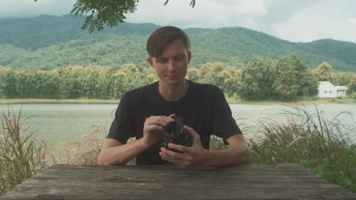 Photographer Adjusting Camera in Mountain Lake Setting
