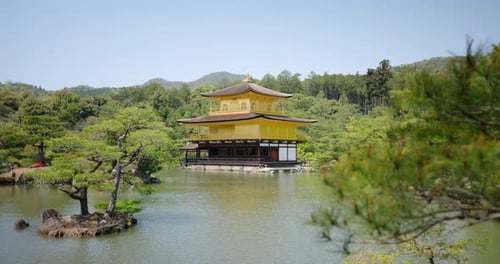 The serene elegance of Kinkaku-ji reflected in calm waters during a sunny day in Kyoto