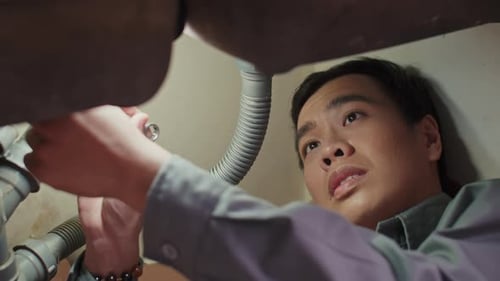 Young Adult Using Wrench to Tighten Pipes