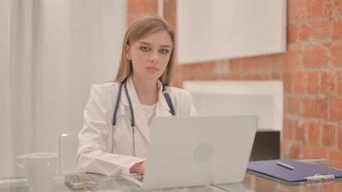 Female Doctor Using Laptop Computer and Smiling