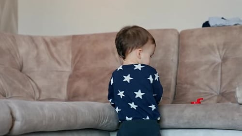 Toddler Plays with Toy Near Couch Indoors