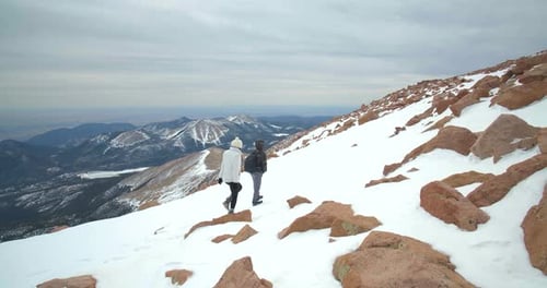 Couple reaching summit together hiking rocky mountains peak adventure in Colorado