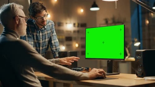 Am Abend arbeitet ein kreativer Mann mittleren Alters an einem Desktop-Computer, grüner Mock-up, Has Conve