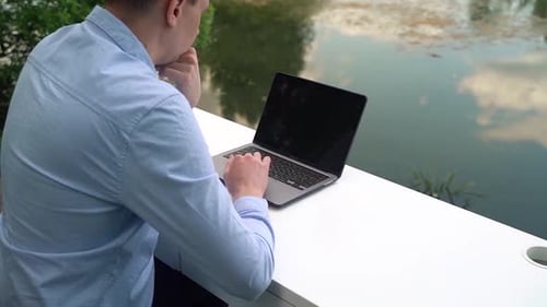 A man works on a laptop outdoors