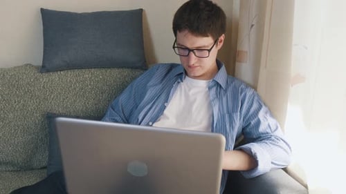 Young Adult Using Laptop at Home on Couch