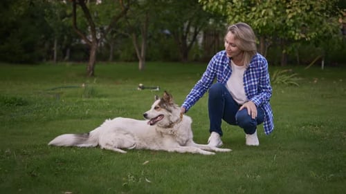 Young Woman in the Garden with Her Dog The Owner Loves Her Pet and is Happy to Spend Time with Him