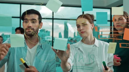 Team Brainstorming Together on Glass Whiteboard in Office