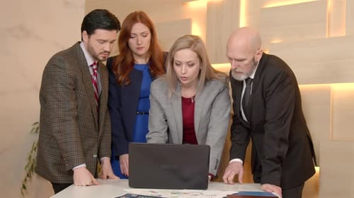 Business Team Discussing Data on Laptop in Office