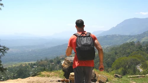 Young Man with Backpack Reaching Up Top of Mountain and Raised Hands Male Tourist Standing on the