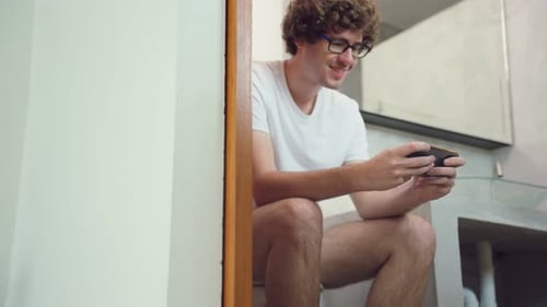 Caucasian handsome man gamer play mobile game on smartphone at home.