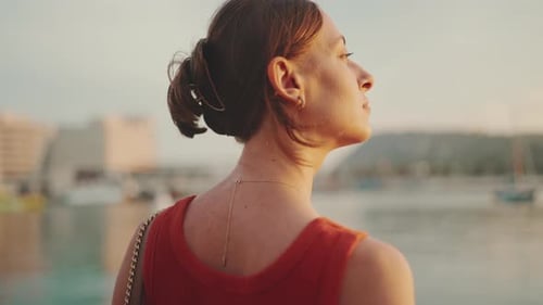 Close-up, girl stands on the seashore and looks at the bay and fixes her hair