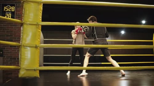Woman Boxing with Trainer in Gym's Boxing Ring