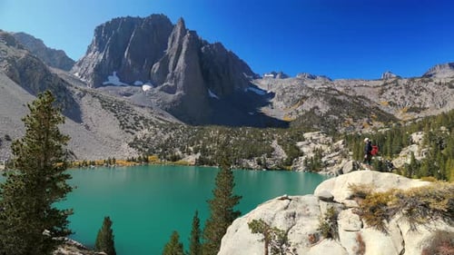 A Stunning Mountain View with a Clear Lake and a Hiker Basking in Bright Sunshine