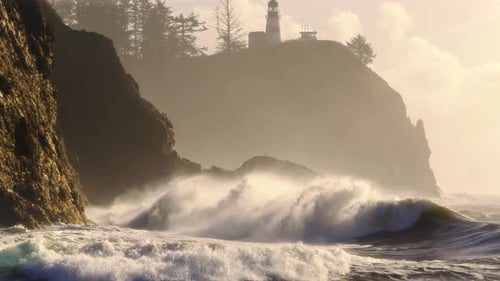 Golden Hour Lighting On Ocean Waves Splashing Rock Cliff With Lighthouse