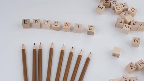 Word "Educate" Spelled out with Blocks and Pencils