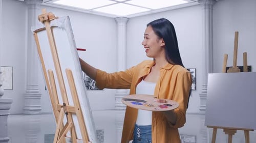 Female Crossing Her Arms And Looking At Picture While Painting On Canvas In Gallery