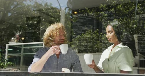 Happy diverse couple drinking coffee and talking in cafe