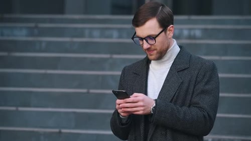 Handsome Man Types On Phone and Smiles