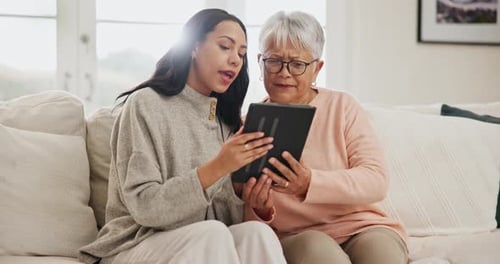 Woman Explains Tablet Use to Senior Woman at Home