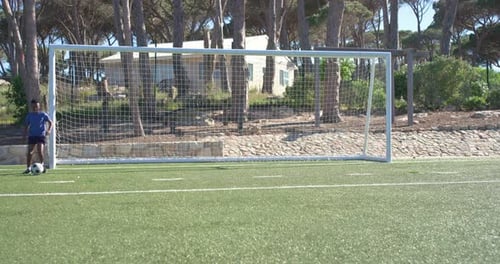 On turf, striker is receiving ball, dribbling and shooting at goal in practice, goalkeeper bracing