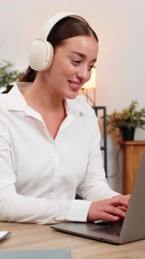 Smiling Woman with Headphones Working on Laptop
