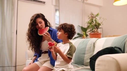 Woman and Child Eating Watermelon Together on Couch