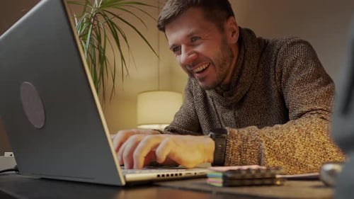 Böswillig lächelnder Mann reibt sich die Hände und tippt auf der Laptop-Tastatur