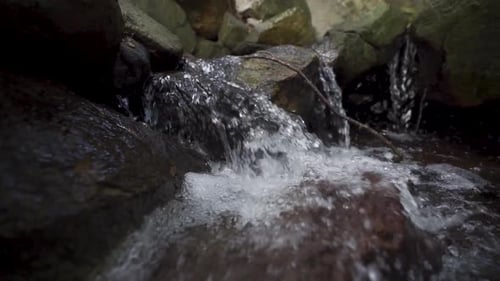 Slow-motion tracking shot of a small stream flowing down rocks