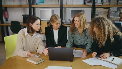 a Group of Young Beautiful Businesswomen Sit at a Round Table and Work with Important Documents
