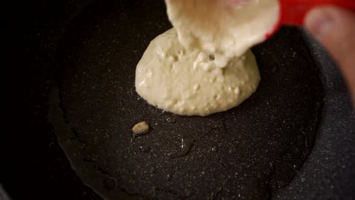 Starting to cook Pancakes. Putting homemade pancake batter into pan in the kitchen