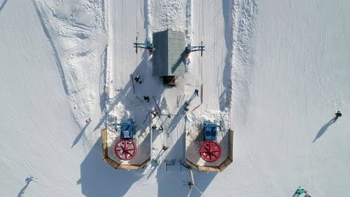 Aerial Top Down View of a Ski Lift Bottom Station Lift Wheels are Spinning Skiers Going Up By Ski