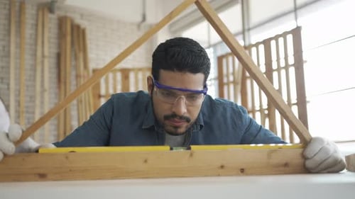 Carpenter is working at woodshop.
