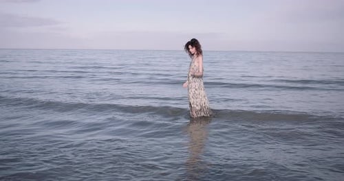 Young adult woman in the sea wearing dress