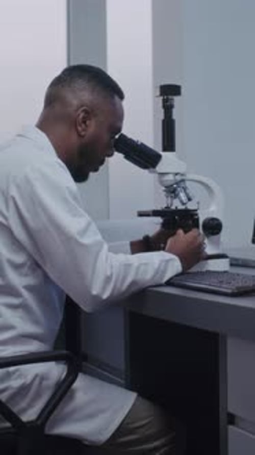 Afroamerikanischer Mikrobiologe schaut unter die Lupe und führt Analysen durch