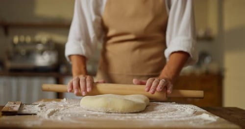 Adult Rolls Dough with Rolling Pin in Kitchen