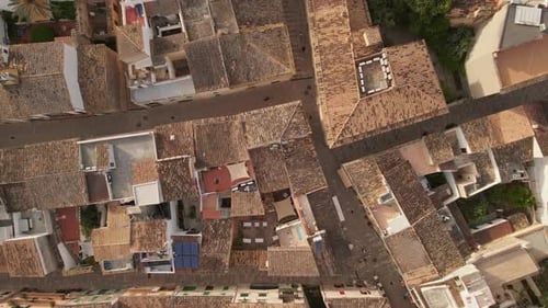 Top-down aerial footage of a Mediterranean town with traditional terracotta rooftops. The video capt