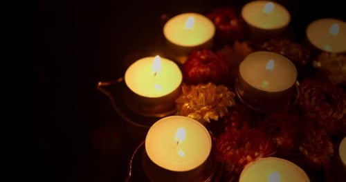Diwali candles and flowers on dark surface