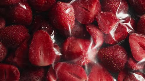 La envasadora al vacío extrae el aire de la bolsa con rodajas de fresa congeladas y preparación para almacenamiento en el congelador
