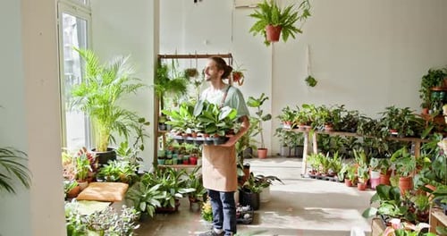 Young Adult Holding Plants in a Plant Shop
