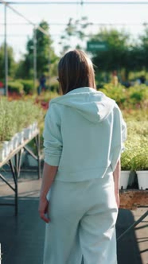Woman Walking Between Plant Rows in Garden Center