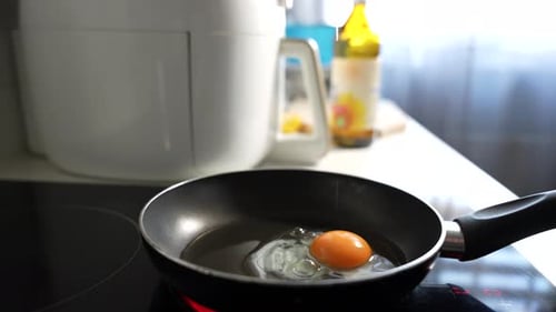 Une personne fait cuire un œuf dans une poêle