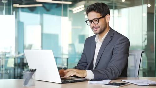 Young Adult Man Works on Laptop in Office
