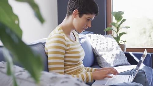 Woman Using Laptop on Couch at Home