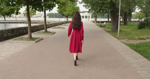 Beautiful positive girl walks in the park near the lake
