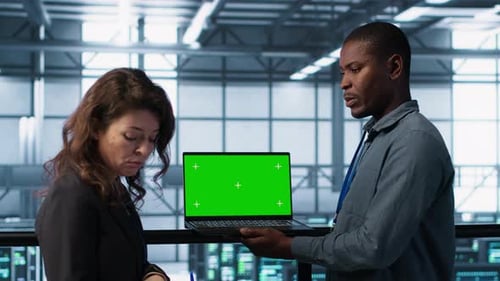 Technicians in Data Center Using Green Screen Mockup Laptop