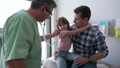Pediatrician Examining Girl on Fathers Lap in Clinic Examination Room 3539 Years