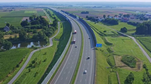Traffic on a highway with many cargo trucks and cars on a beautiful green and natural location.