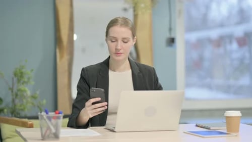 Woman Using Phone at Desk in Modern Office