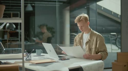 Young Engineer Architect Working on New Project in Modern Office with Blueprints
