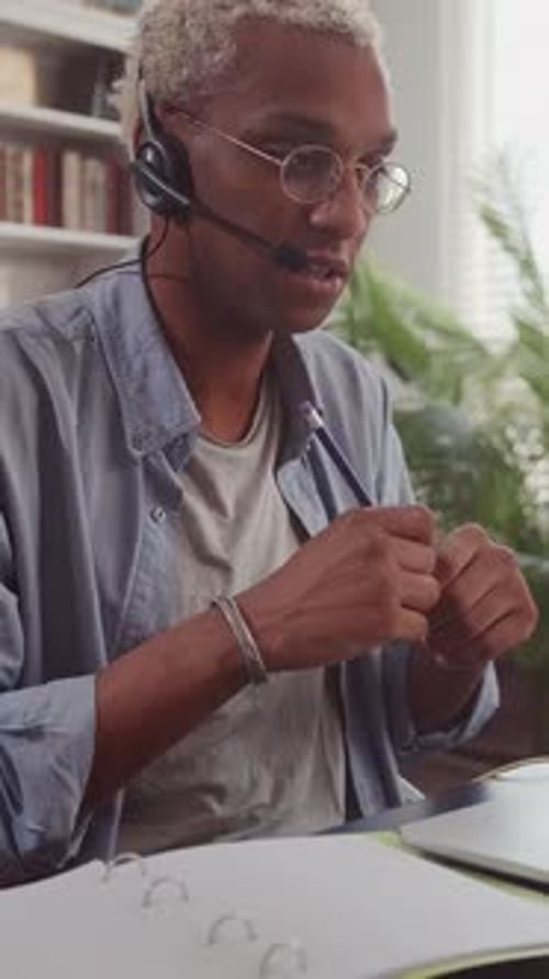Homme afro-américain blond avec casque parlant et prenant des notes